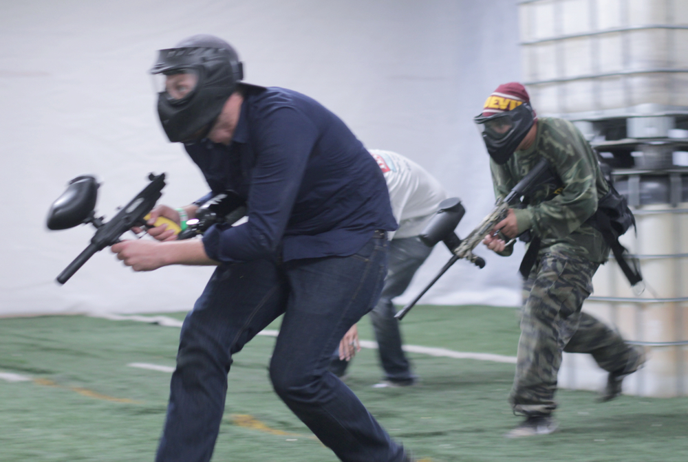 Paintball players running onto the indoor paintball field.