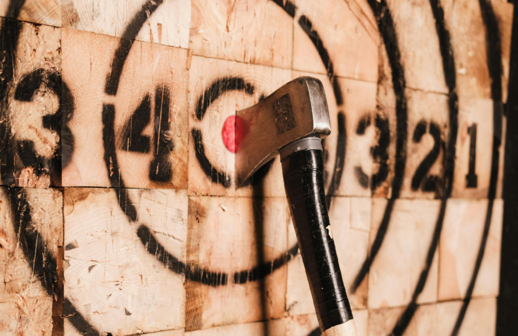 An axe in an axe throwing board. American Paintball Coliseum offers axe throwing near Denver, Co